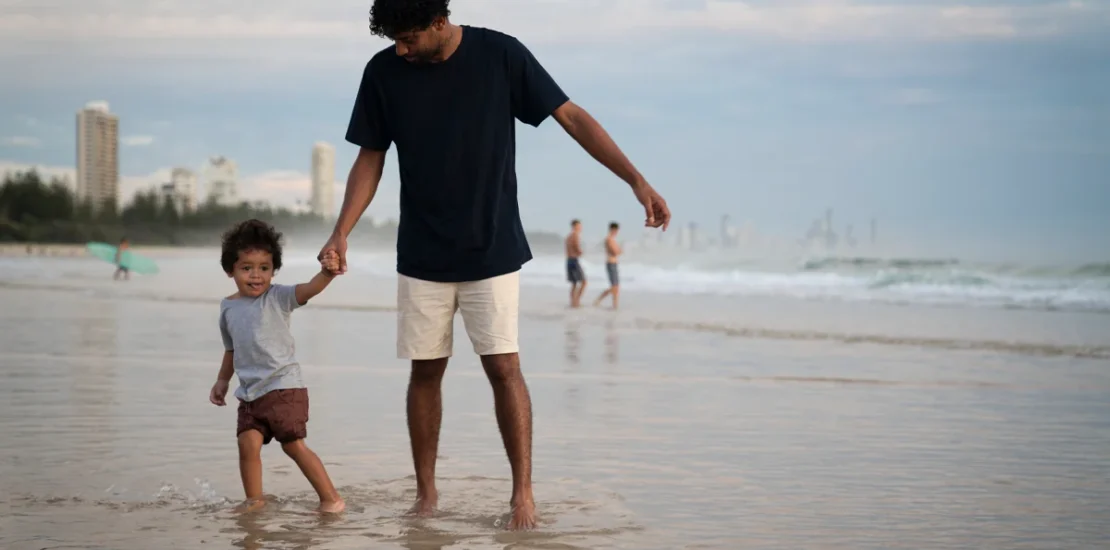 Father and child on the beach with the Gold Coast city in the background