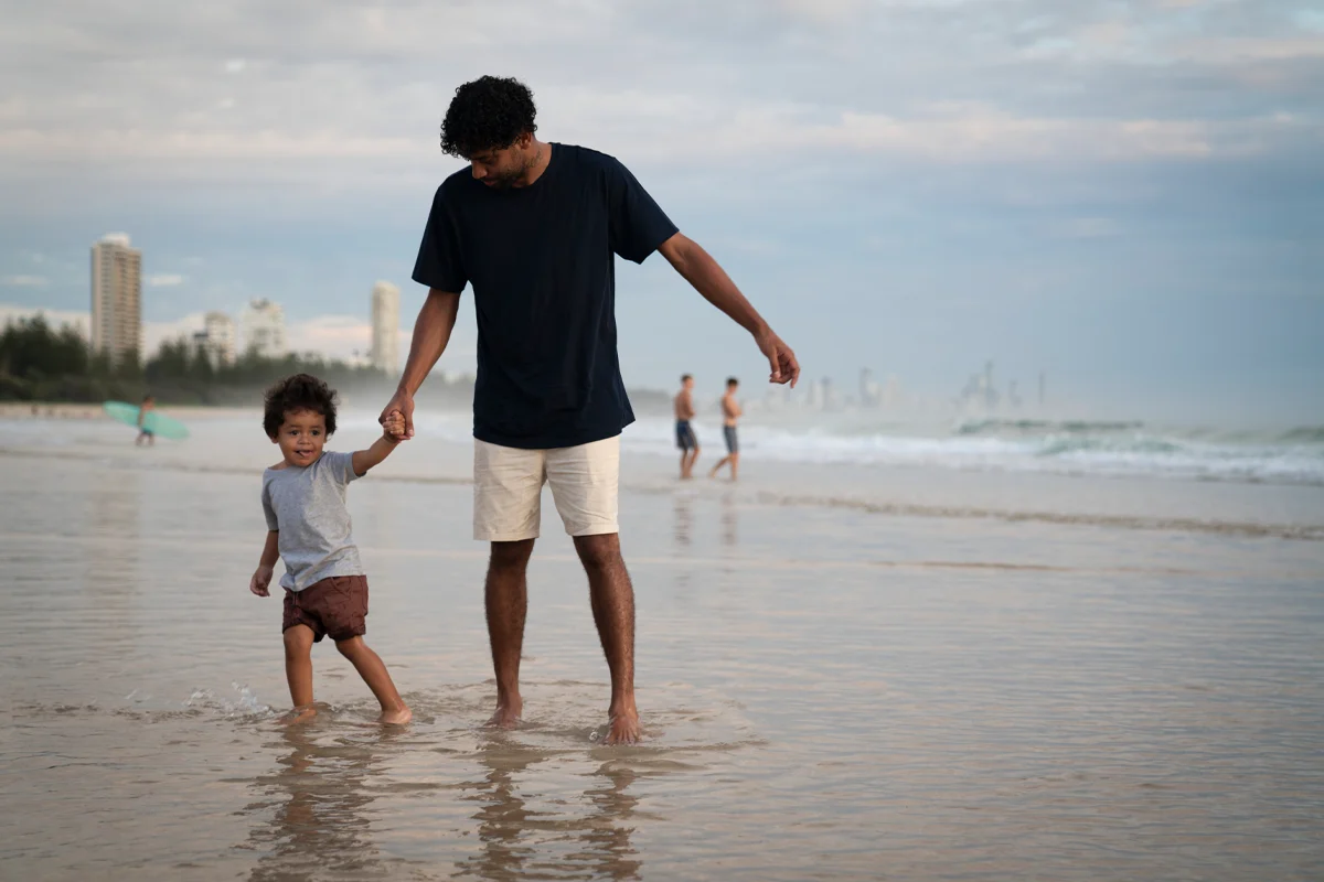 Father and child on the beach with the Gold Coast city in the background